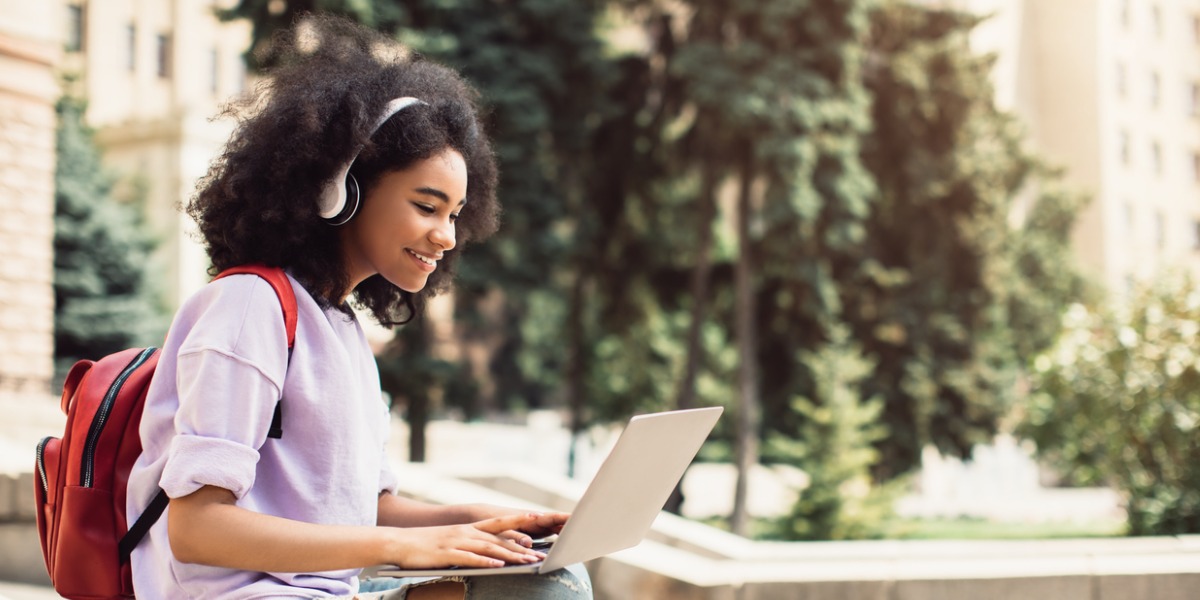 african-american-female-student-using-laptop-learning-sitting-outdoor